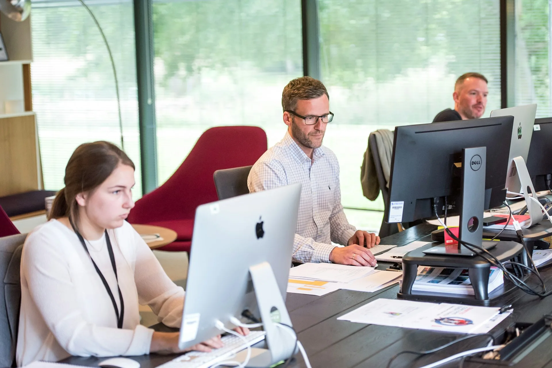 Twee mensen aan het werk achter een beeldscherm bij het raam