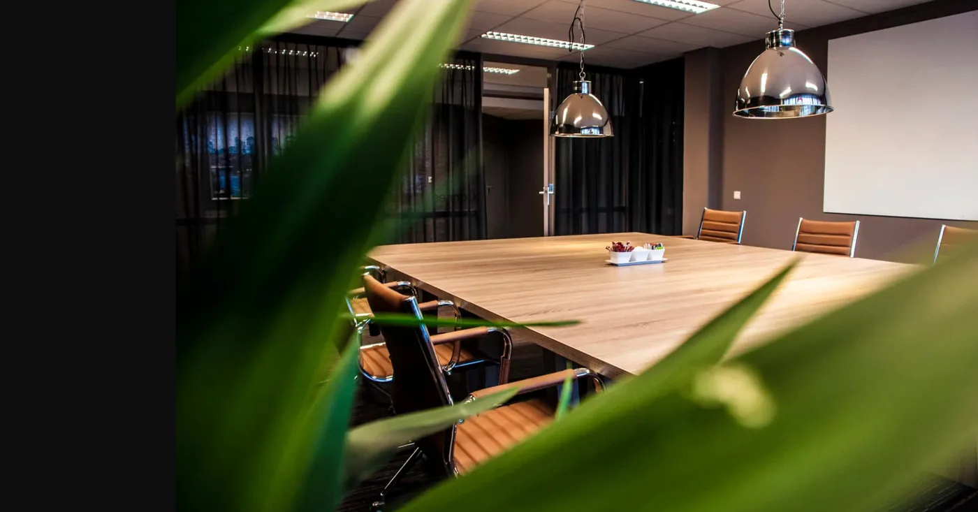 Vergadertafel met hanglampen, gezien door het groen