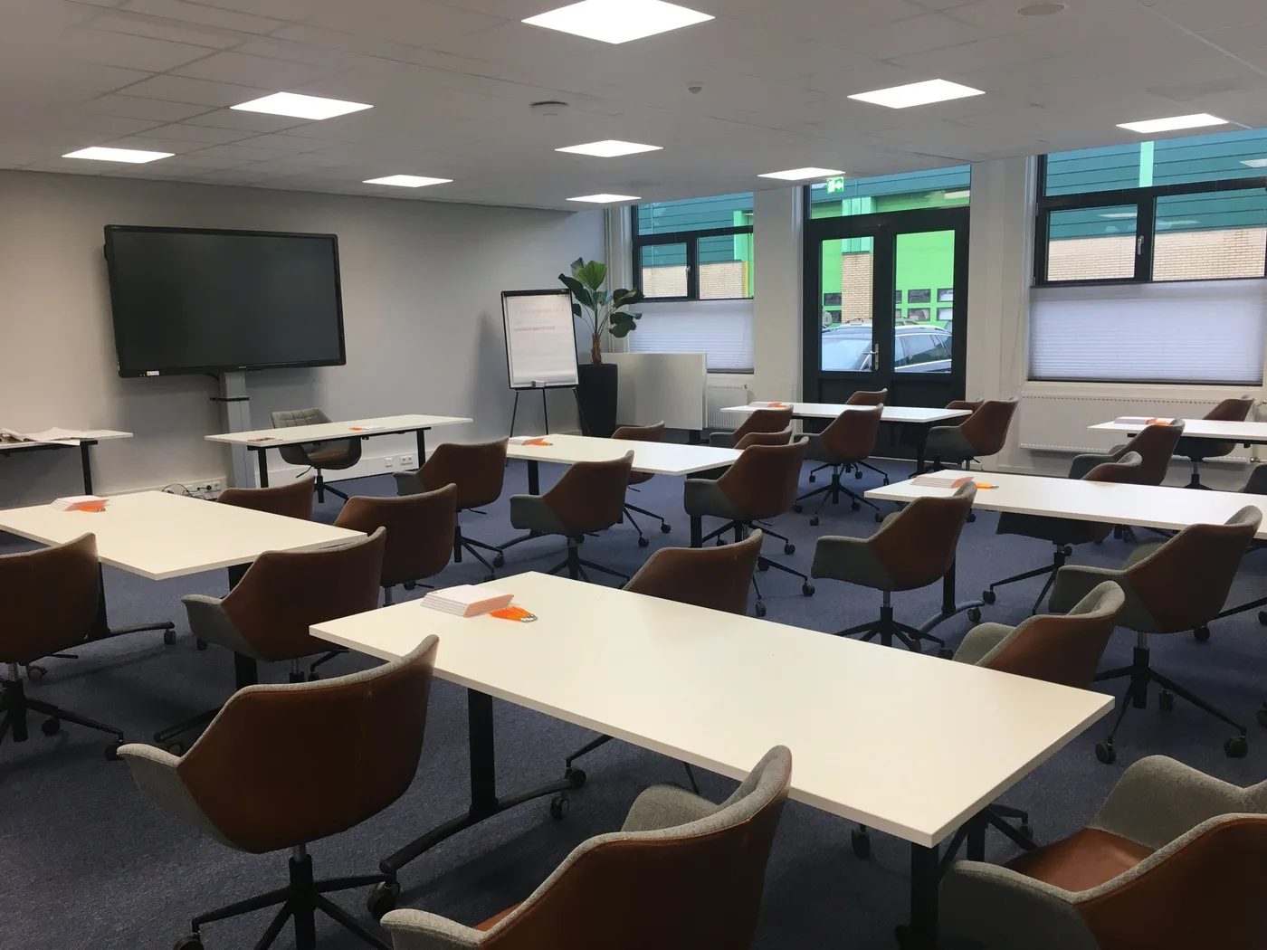 Vergaderzaal met tafels in blokopstelling en een groot scherm