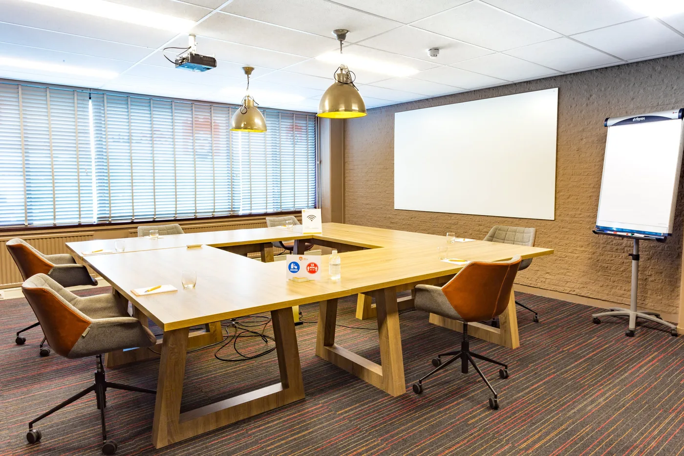 Vergaderzaal met houten tafels in blokopstelling